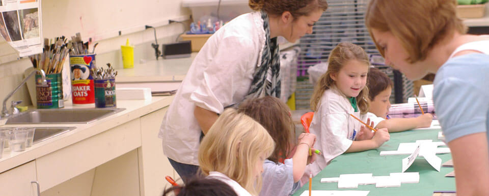 Student teachers help their students with their art.