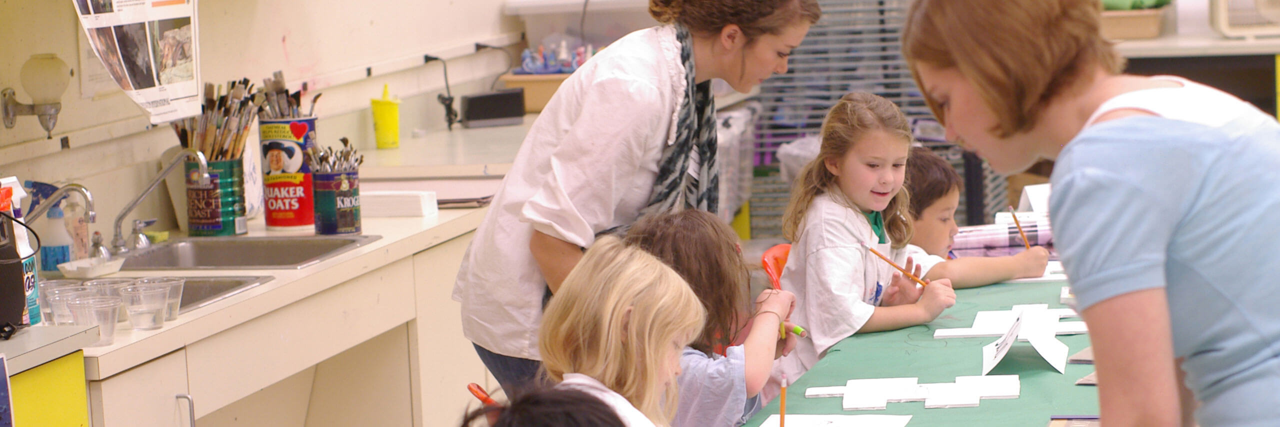 Student teachers help their students with their art.