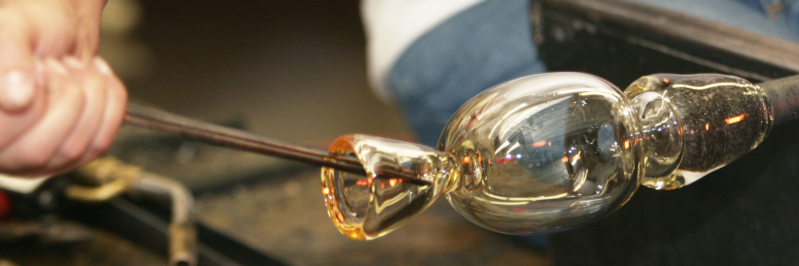Student works on a glass-blown piece of art.