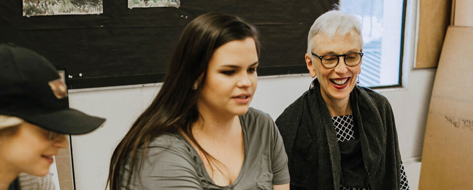 Two future art teachers meet with their professor.