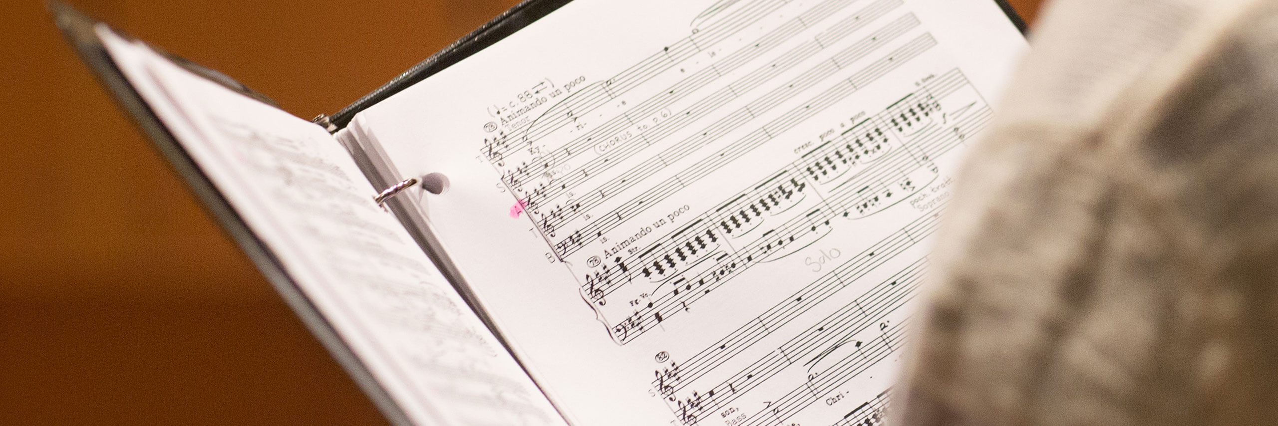 Sheet music in a binder being held by a vocalist.