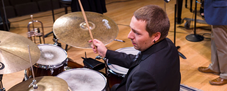 A drummer performs with the rest of the jazz band.
