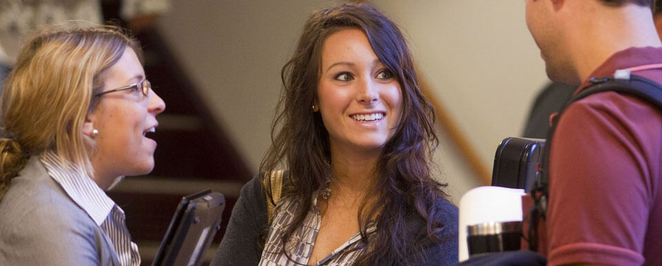 Three students in business attire have a discussion.