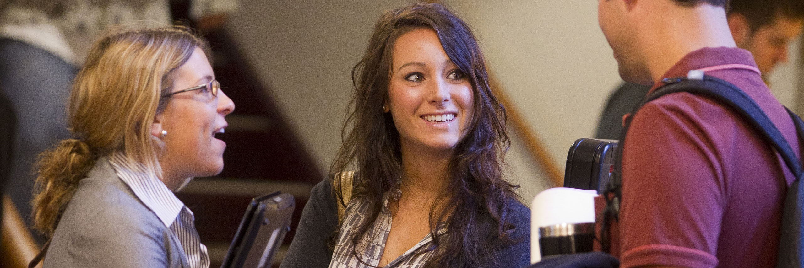 Three students in business attire have a discussion.