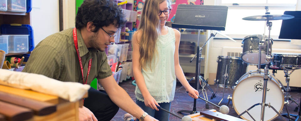 A student teacher teaches percussion to his student.