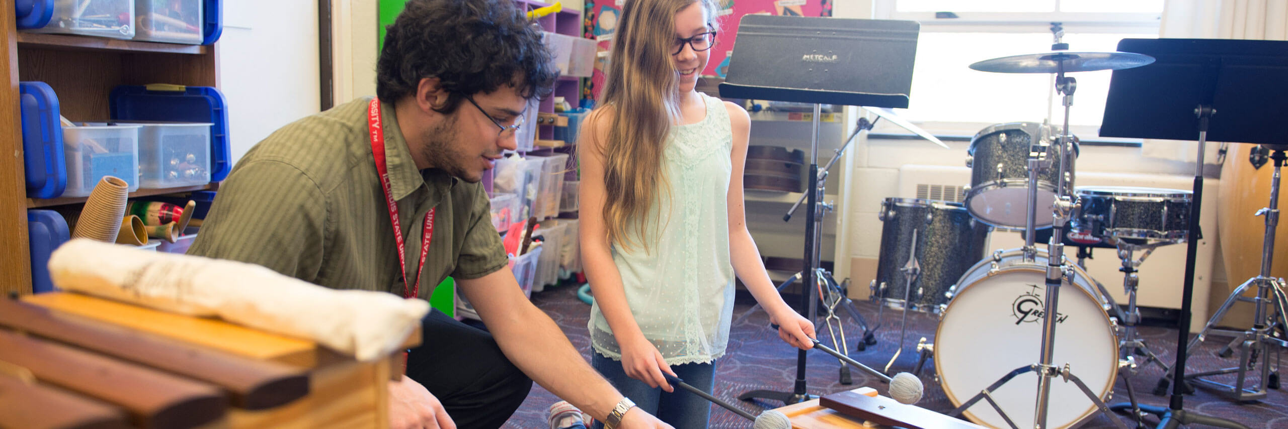 A student teacher teaches percussion to their student.m