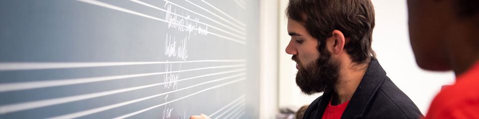 Student writes on the chalkboard.
