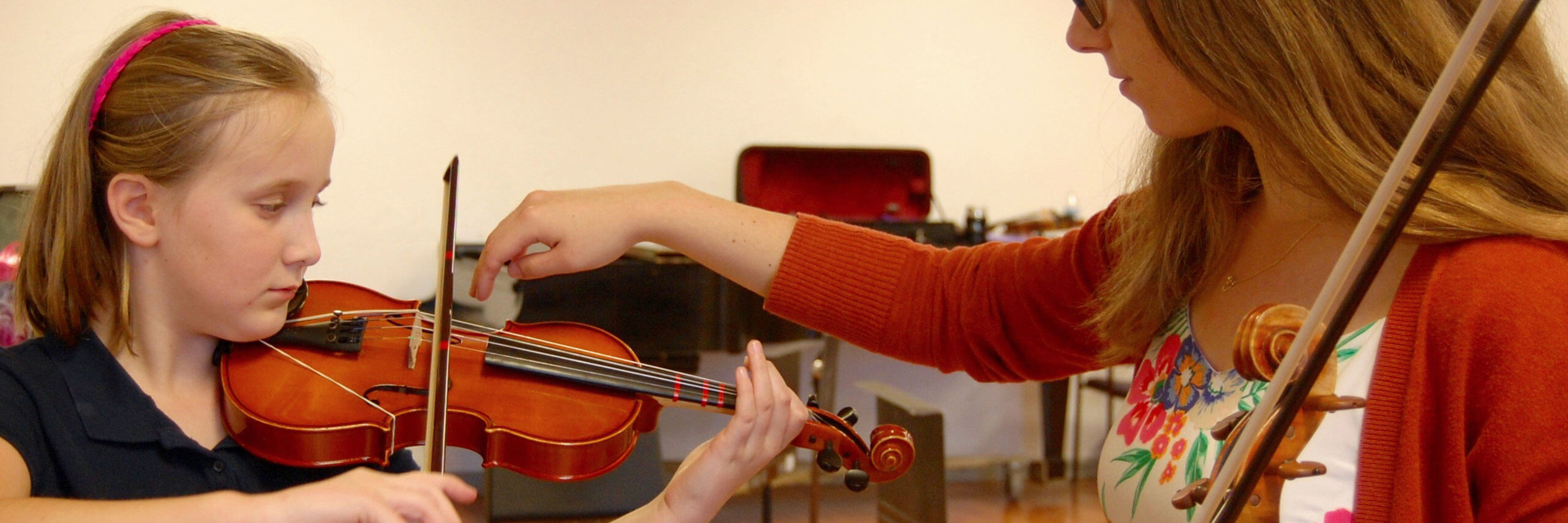 A student teacher gives a violin lesson to their student.