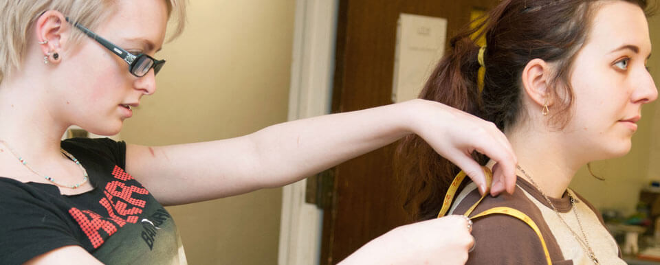 Student tailors a costume for an actress.