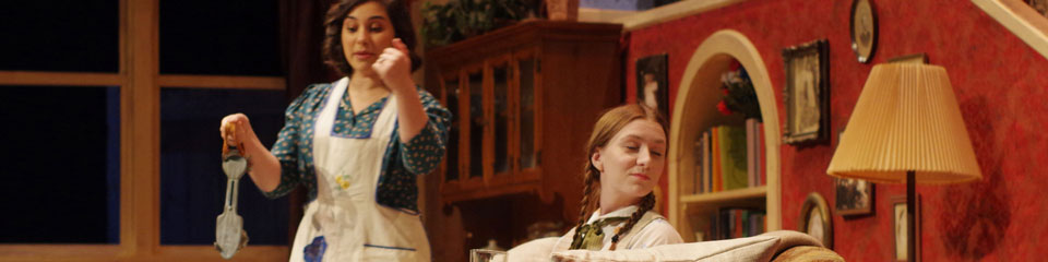 Two actresses perform on a set of a living area.