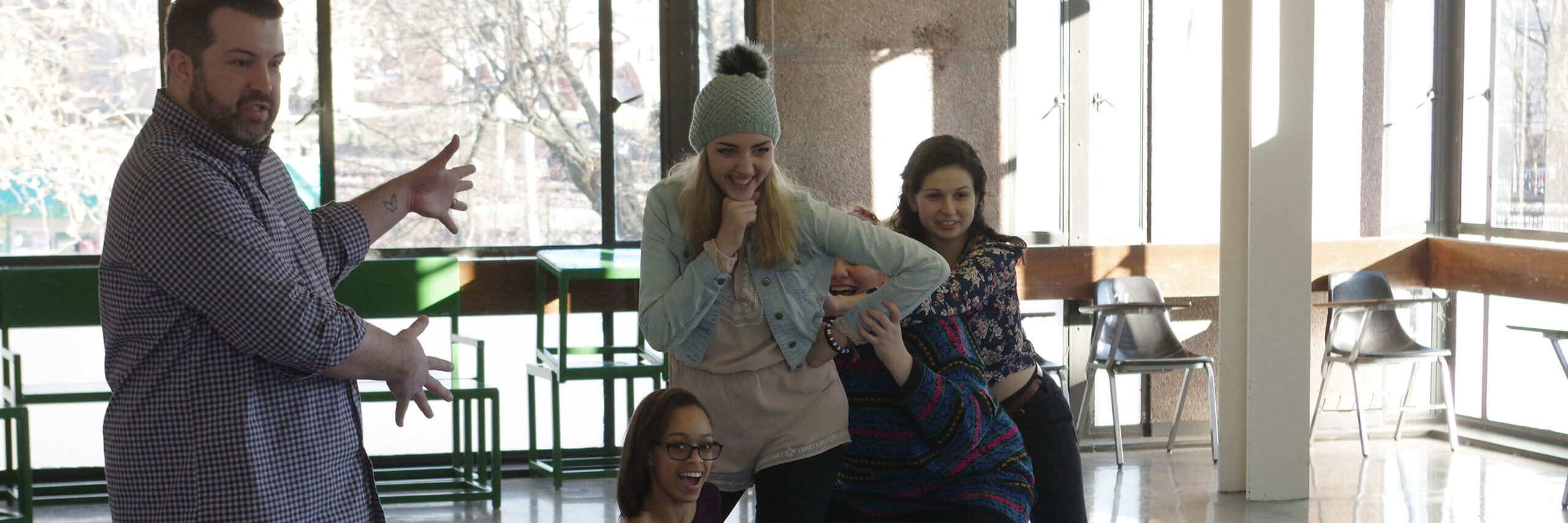 A teacher and his students rehearse a skit during class.