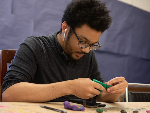 A sculpture student sculpts with polymer clay.