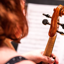 A student rests her violin and follows her music.