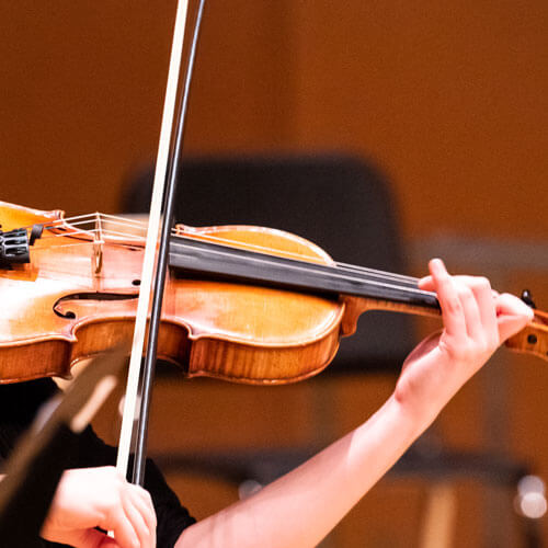 Student plays her violin in an ensemble.