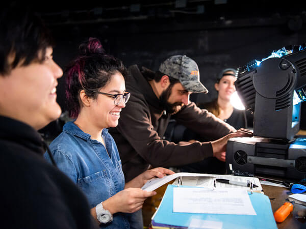 Lighting production students work behind the scenes on a spotlight.